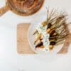 bowl of carrots with yogurt sauce sitting on a cutting board and a loaf of sourdough bread in the background