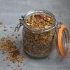 jar filled with granola and a little bit spilled on the ground next to the jar