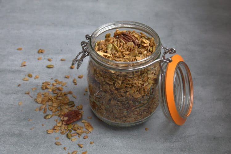 jar filled with granola and a little bit spilled on the ground next to the jar