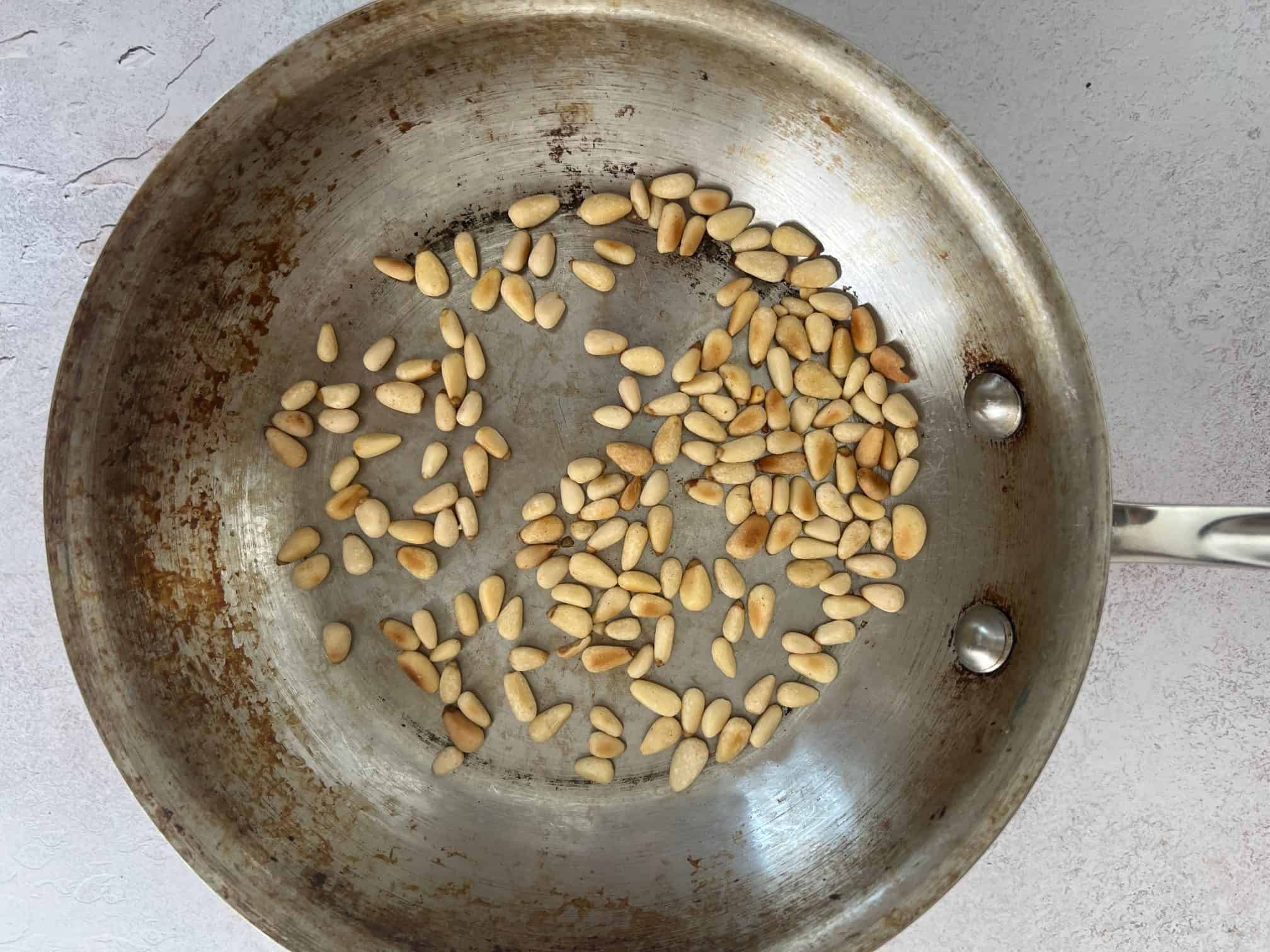 pine nuts toasting in a pan