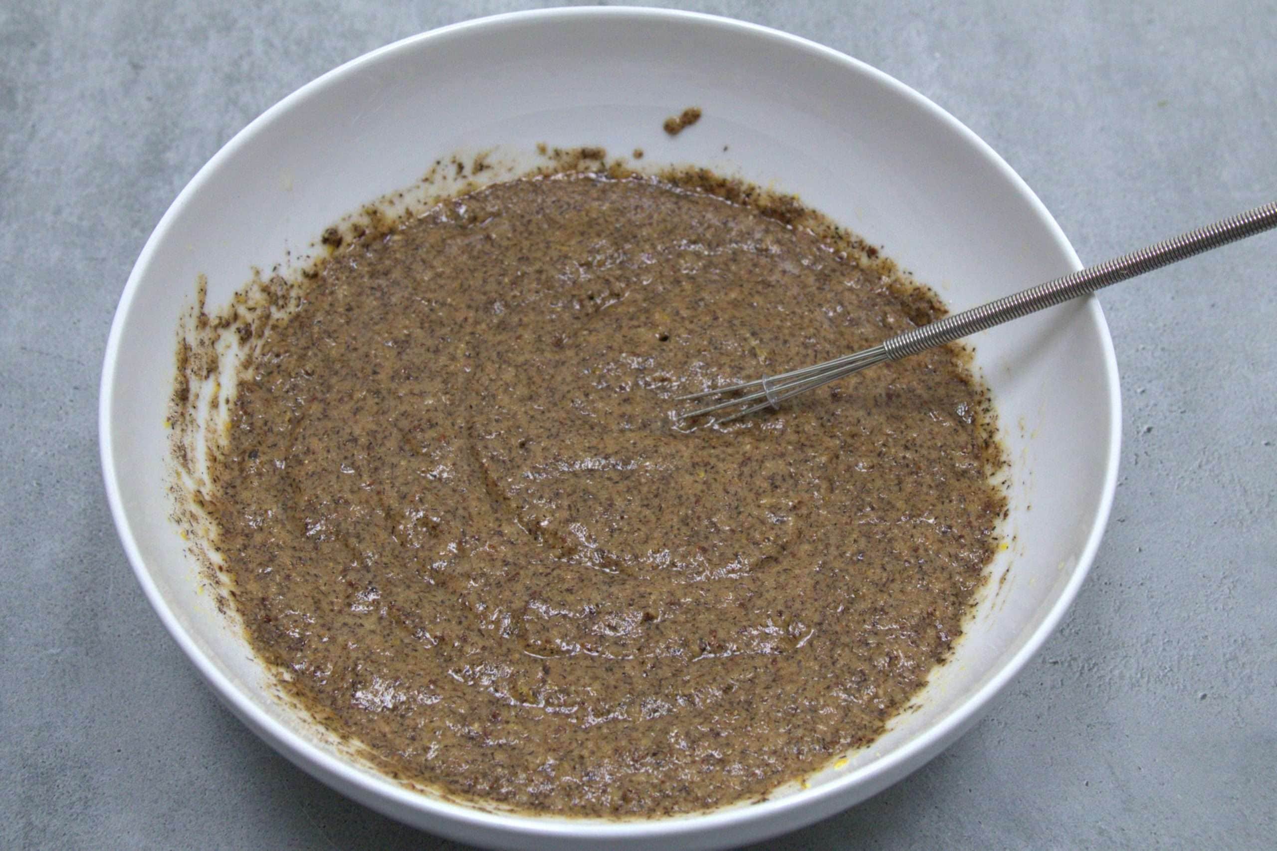 Batter for hazelnut apple coffee cake in a white bowl with a small whisk resting on the side