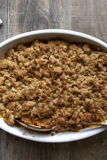 Baking dish with pear crisp and a white and red napkin on the side