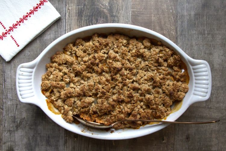 Baking dish with pear crisp and a white and red napkin on the side