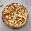 Pear and almond coffee cake with a serving utensil and whole cloves in the background