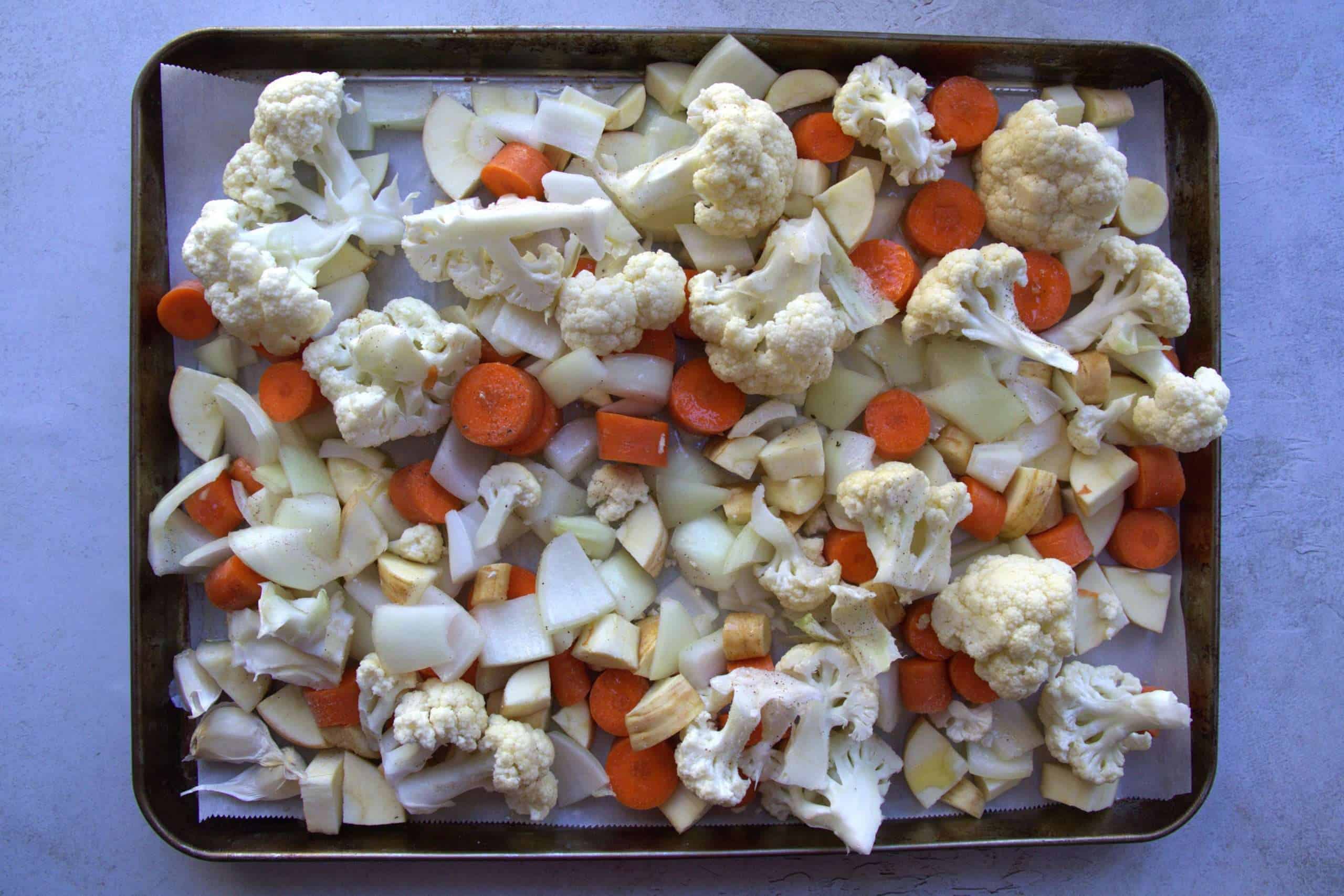 vegetables for fall vegetable soup on a baking sheet ready to go in the oven