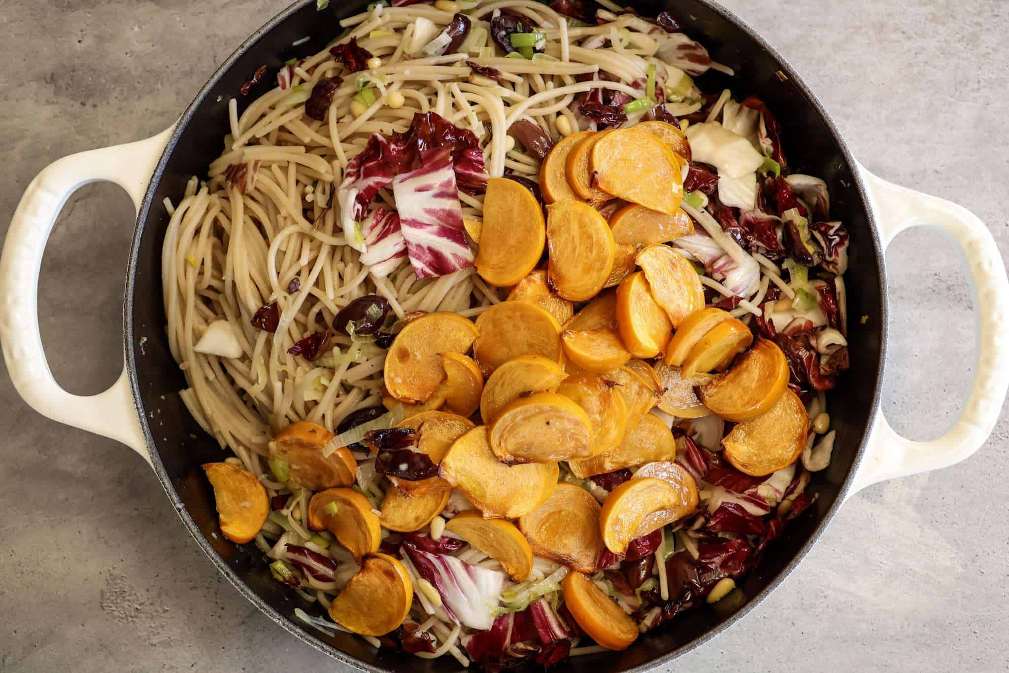 Roasted persimmon and radicchio pasta in a pan, ready to be tossed