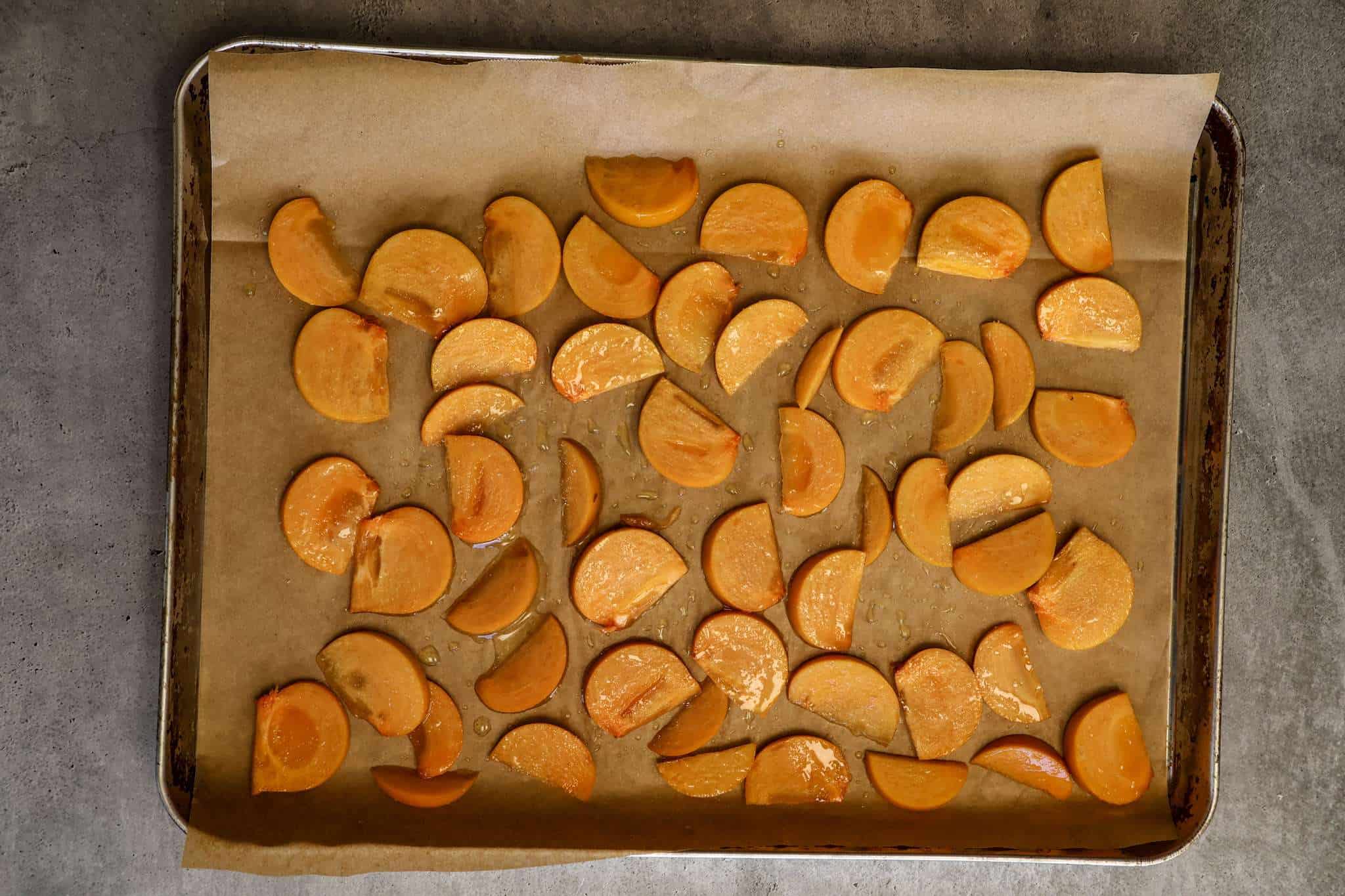 sliced persimmon wedges on a parchment lined baking sheet