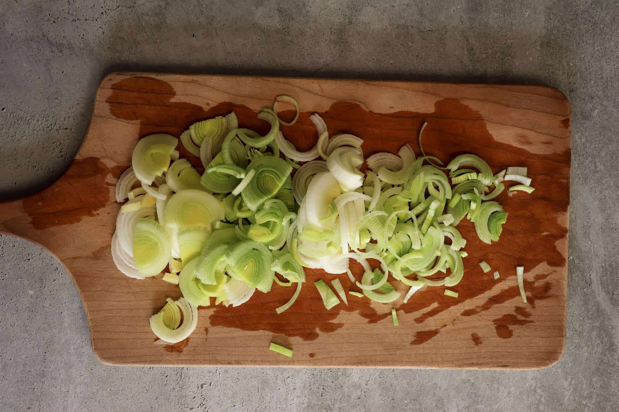 thinly sliced leeks on a wooden board