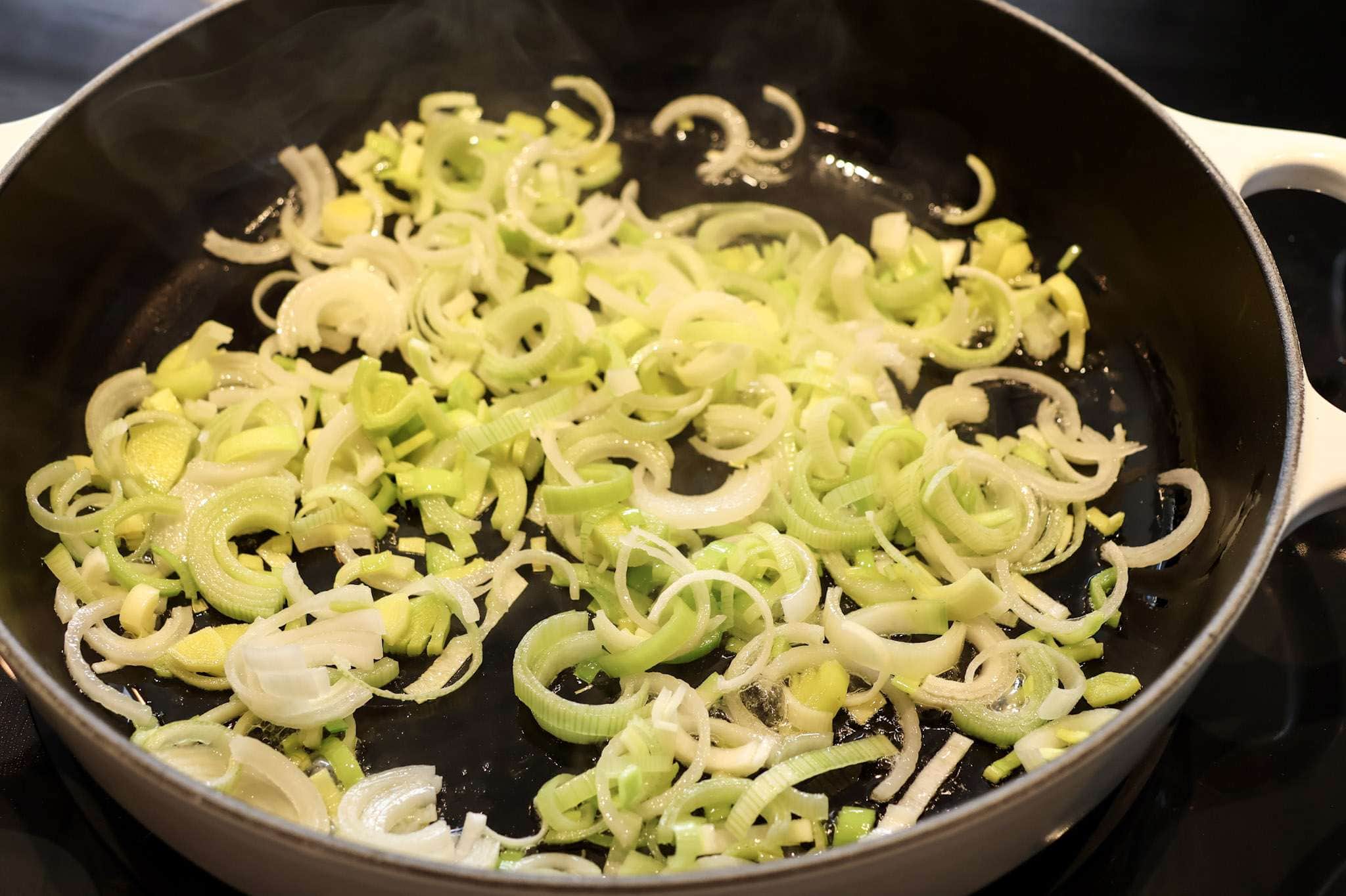thinly sliced leeks sauteing in a pan