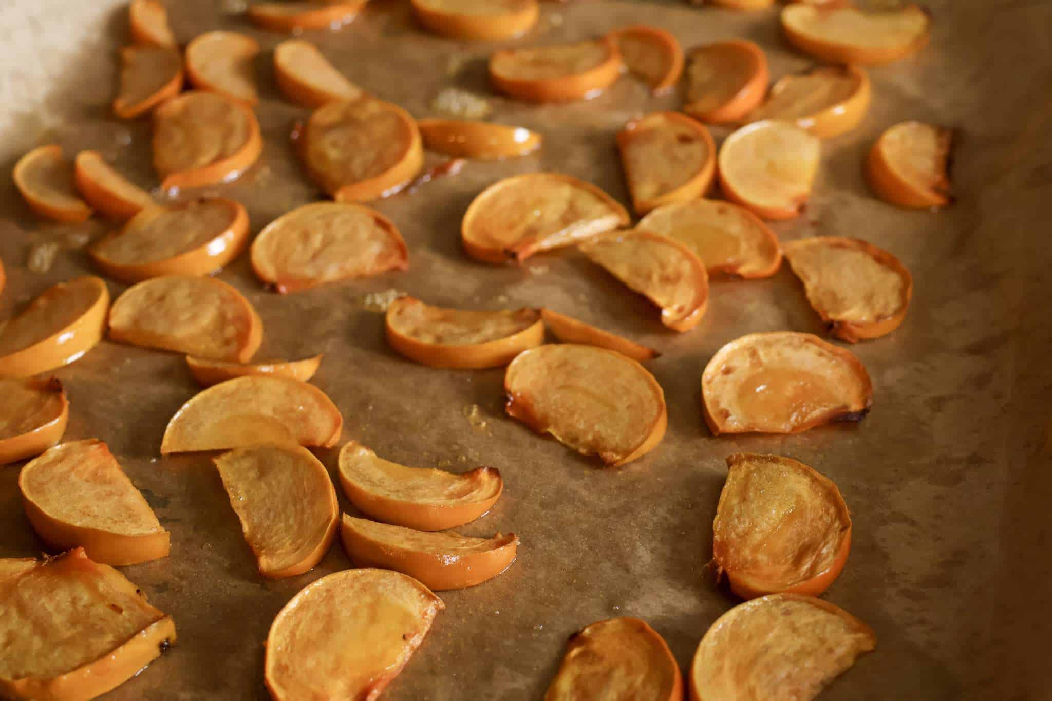 roasted persimmon wedges on a parchment lined baking sheet