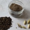 jar of ground cardamom with seeds and pods next to it