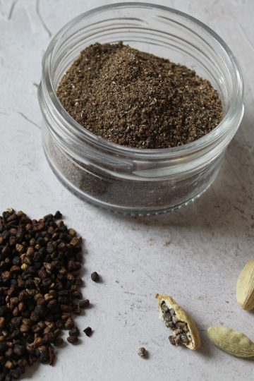 jar of ground cardamom with seeds and pods next to it