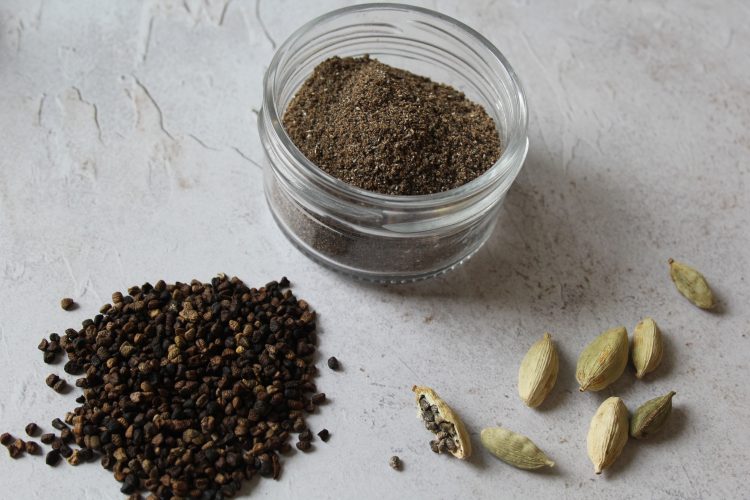 jar of ground cardamom with seeds and pods next to it