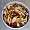 a bowl with salad made up of radicchio, sliced pears, fennel, pecans, shaved pecorino romano cheese and dressing