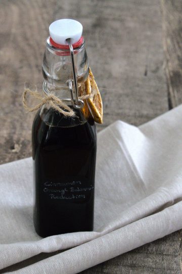 bottle of cinnamon orange balsamic reduction with a bow and a slice of dried orange around it
