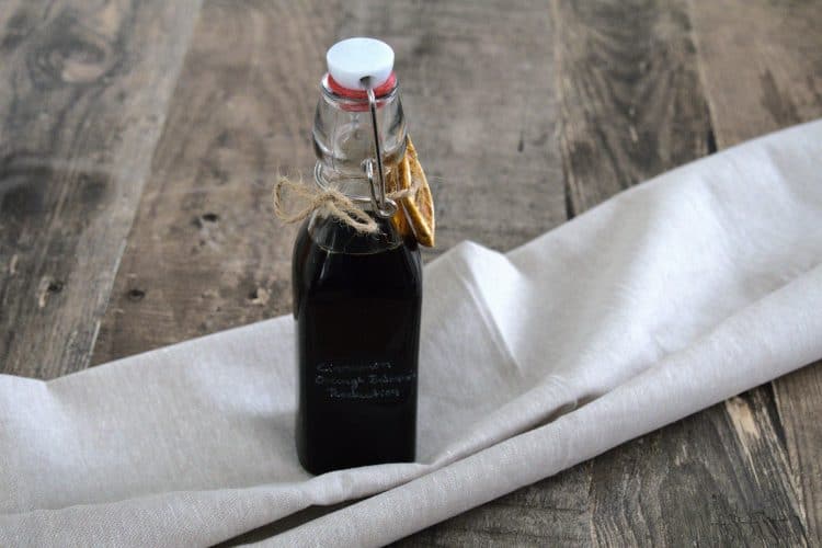 bottle of cinnamon orange balsamic reduction with a bow and a slice of dried orange around it