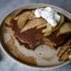 plate of gingerbread pancakes topped with pears and yogurt, a fork resting on the side with a piece of pancake on it and a napkin on the side