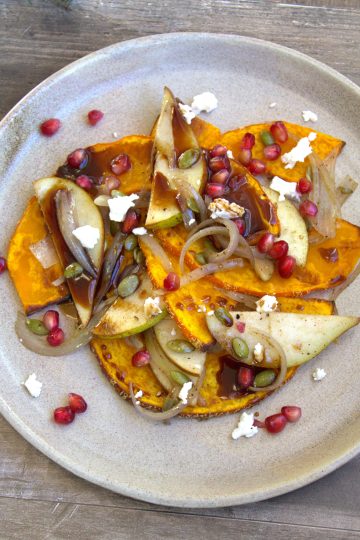 plate with roasted squash, shallots, pears, goat cheese, pomegranate seeds and a drizzle of balsamic reduction