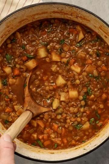 A Dutch oven with celeriac and lentil soup and a wooden ladle resting in it