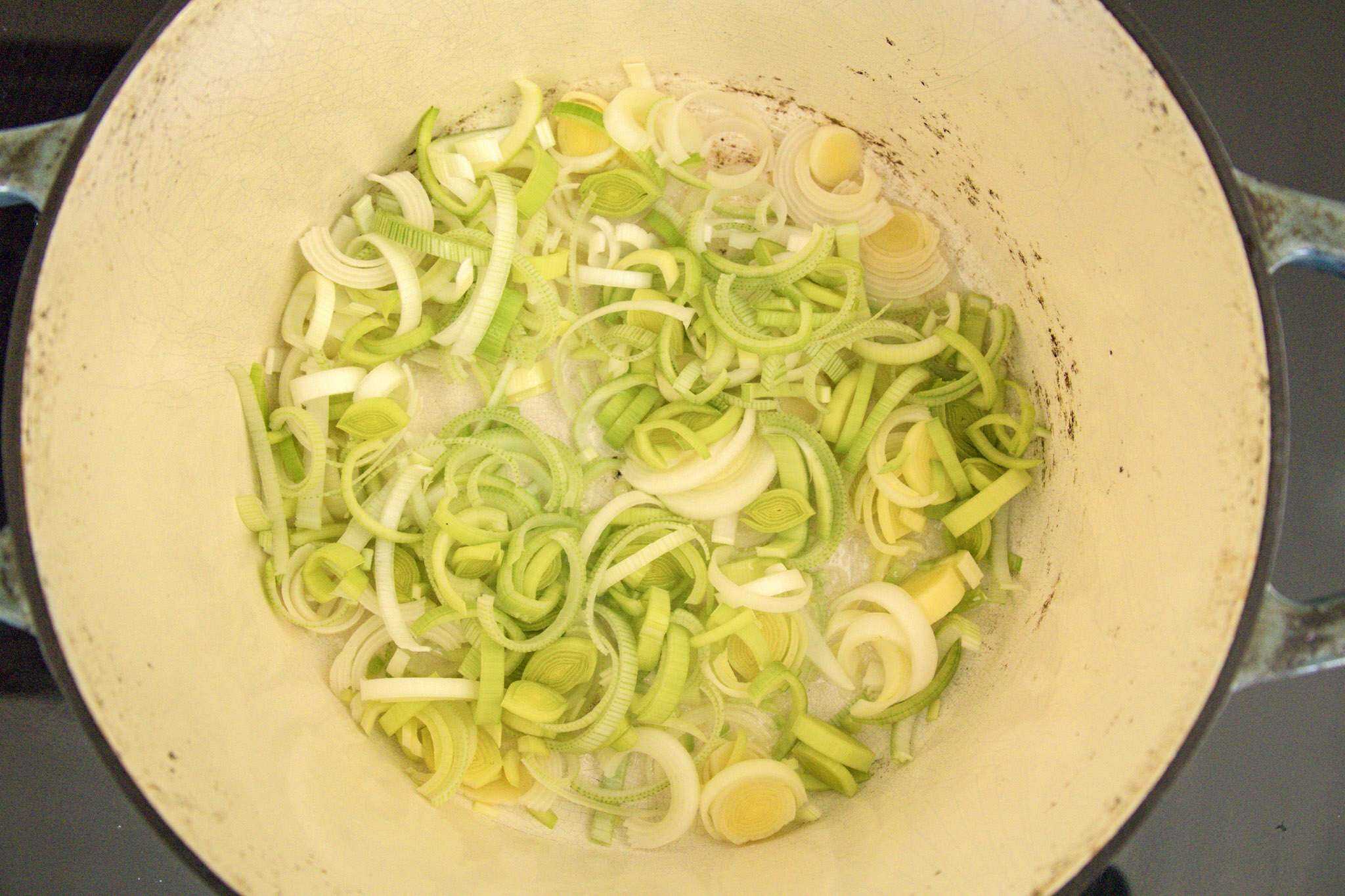 thinly sliced leeks sauteing in a pot