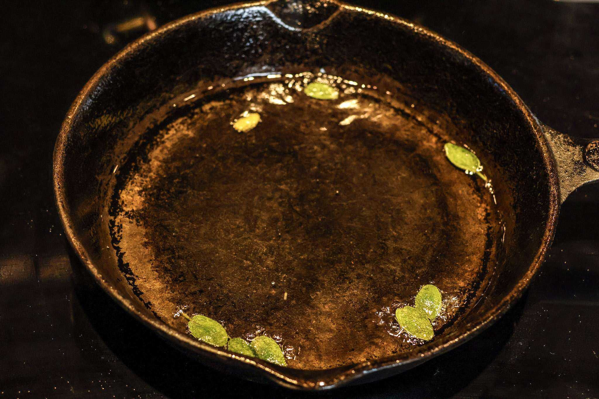 a small cast iron pan with sage leaves frying in it
