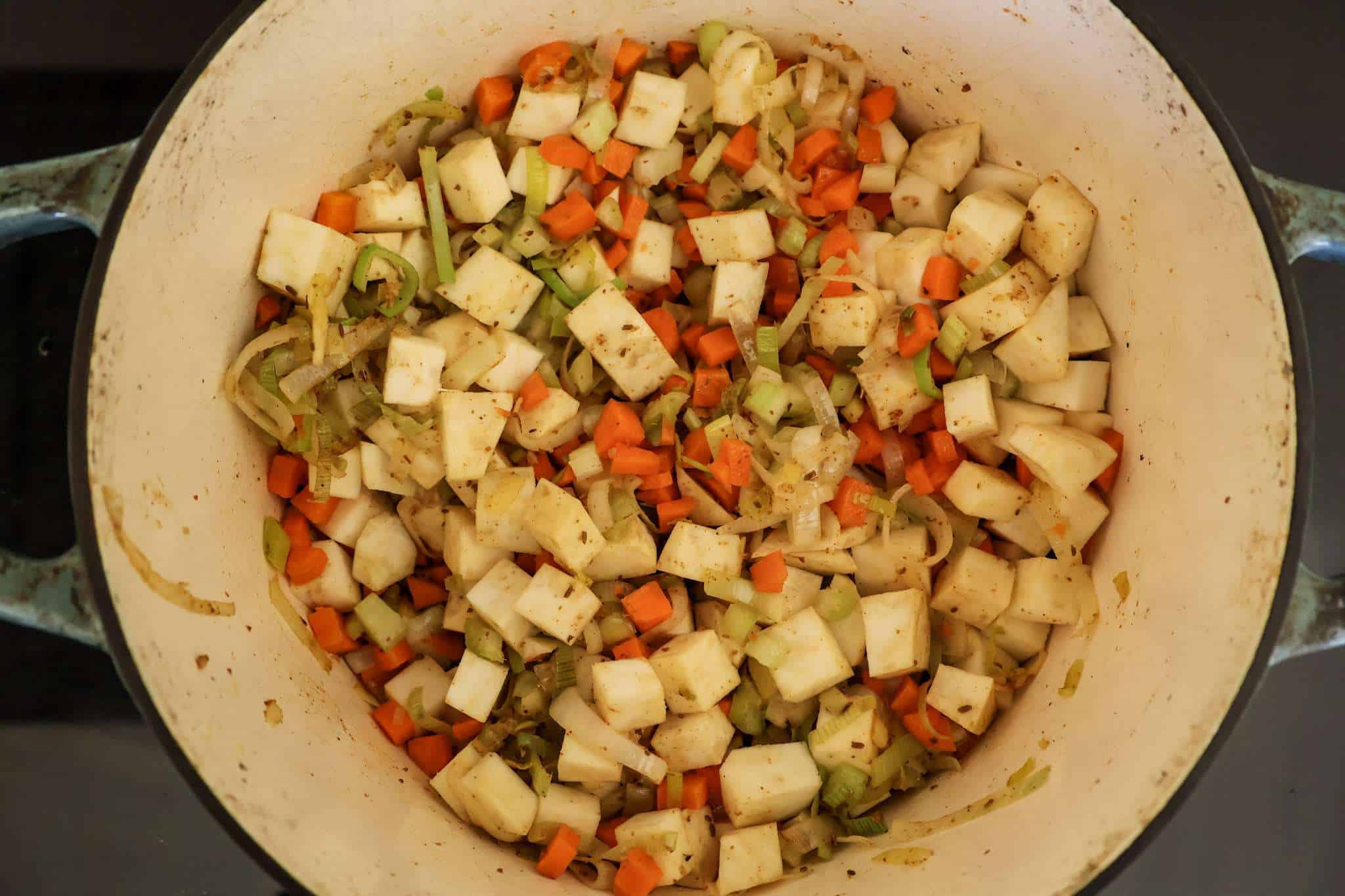 Leeks, spices, carrots, celery, garlic and celery root are cooking in a pot