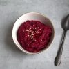 bowl with beet pesto and sesame seeds sprinkled on top and a spoon resting next to the bowl