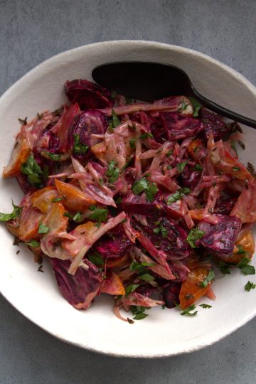 Bowl with beet salad and a spoon resting in it and napkin in the background
