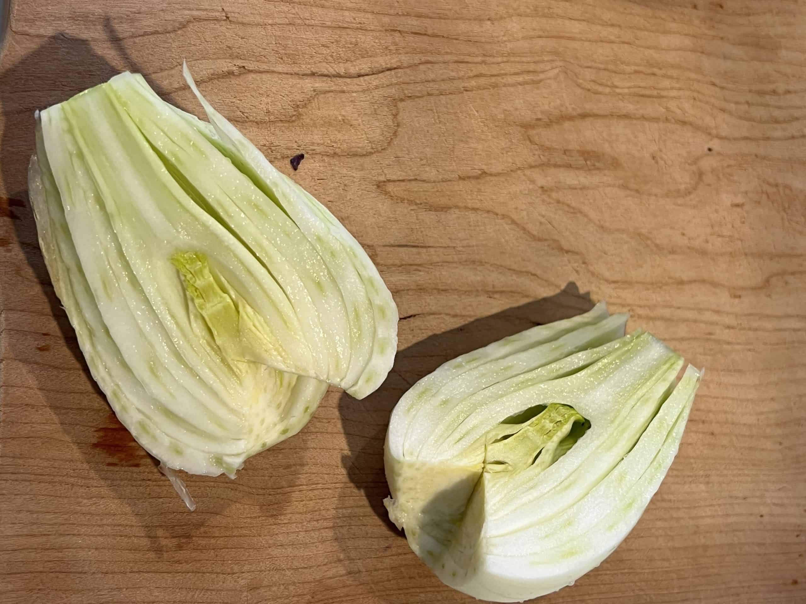two cored fennel halves on a cutting board