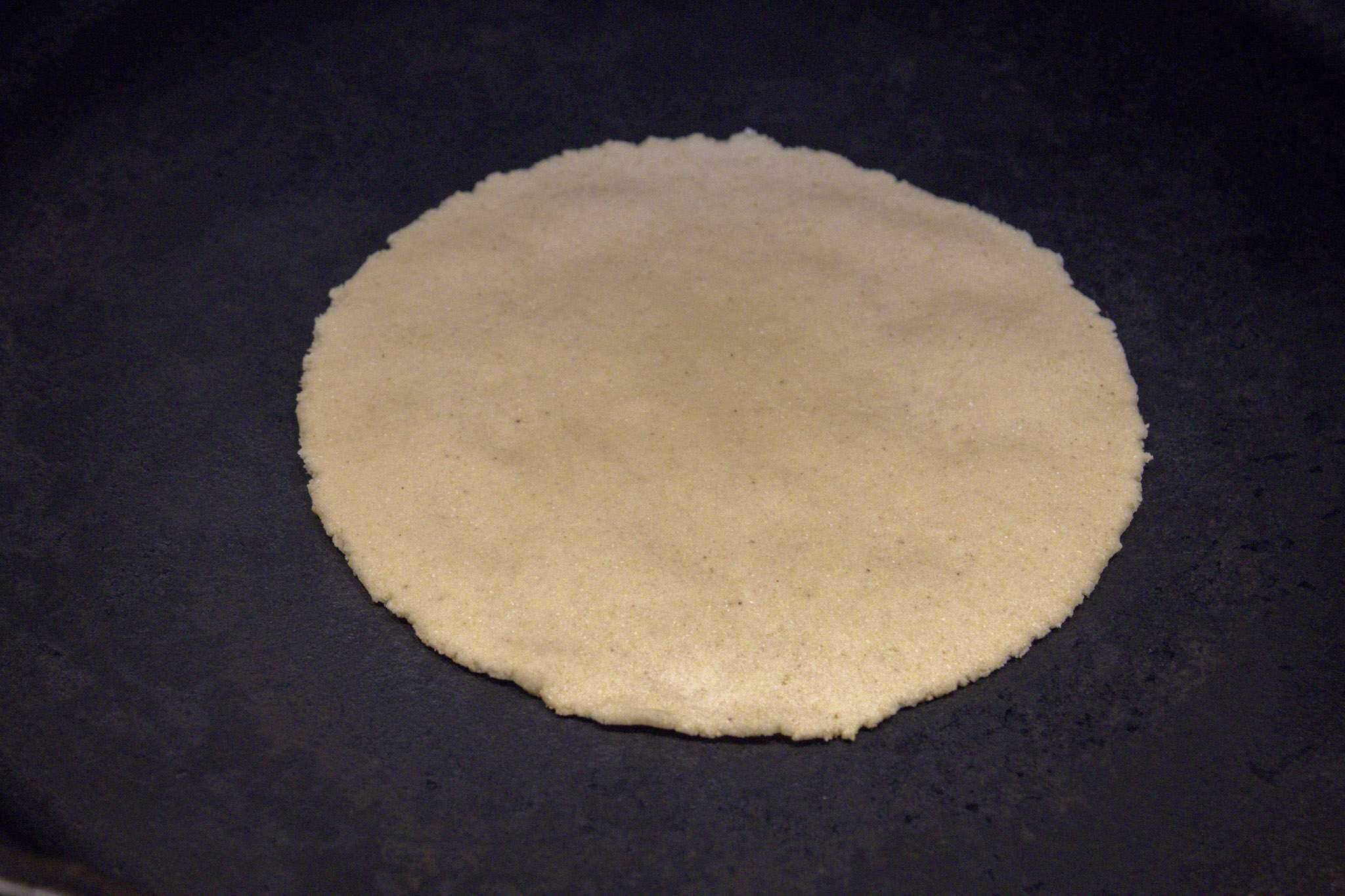 a pressed tortilla in a pan displaying some light bubbles