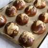 a parchment lined baking sheet holding pretzel rolls is resting on a white wood surface