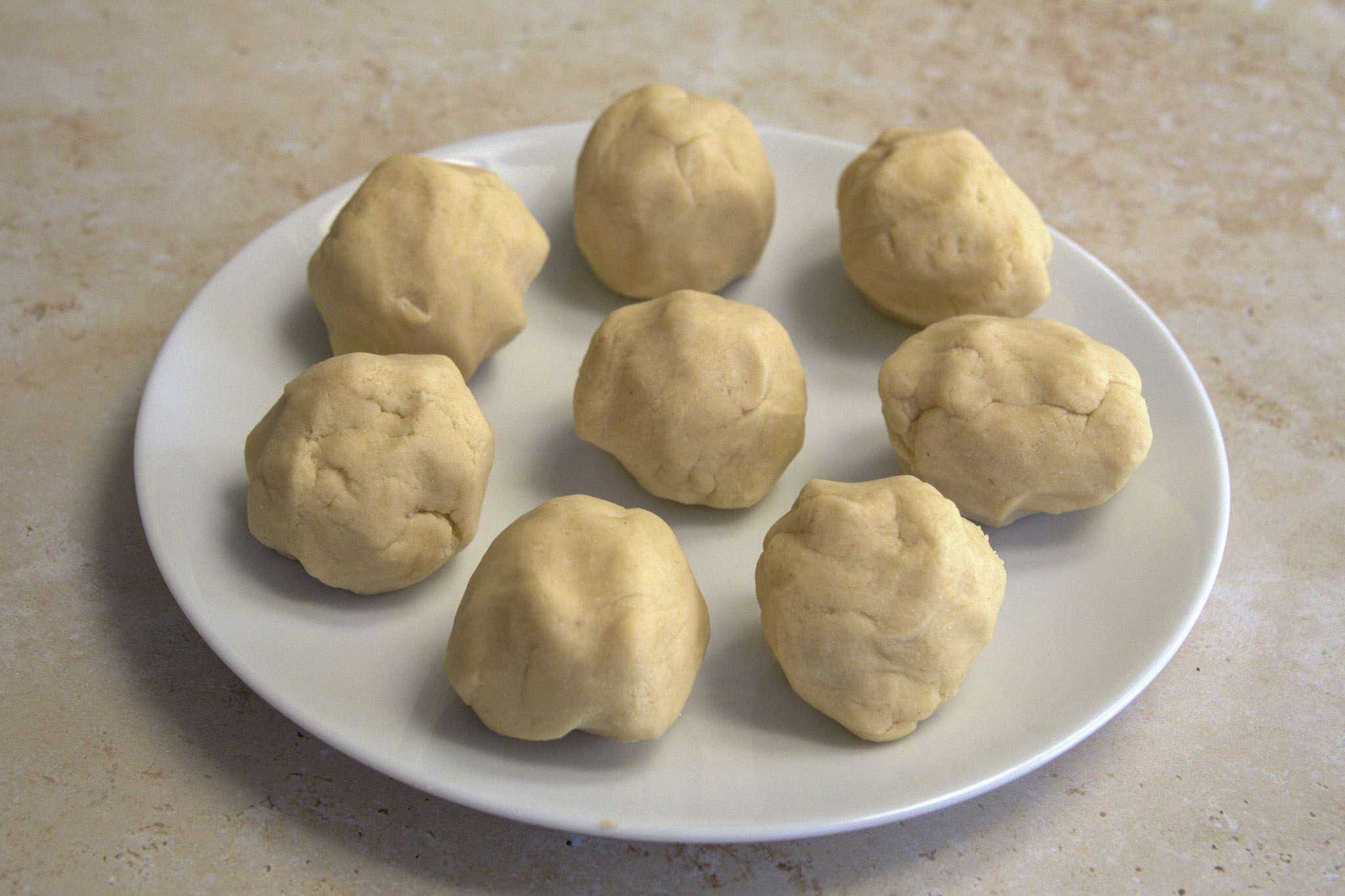 the dough for chickpea and cassava tortillas divided into 8 balls on a white plate