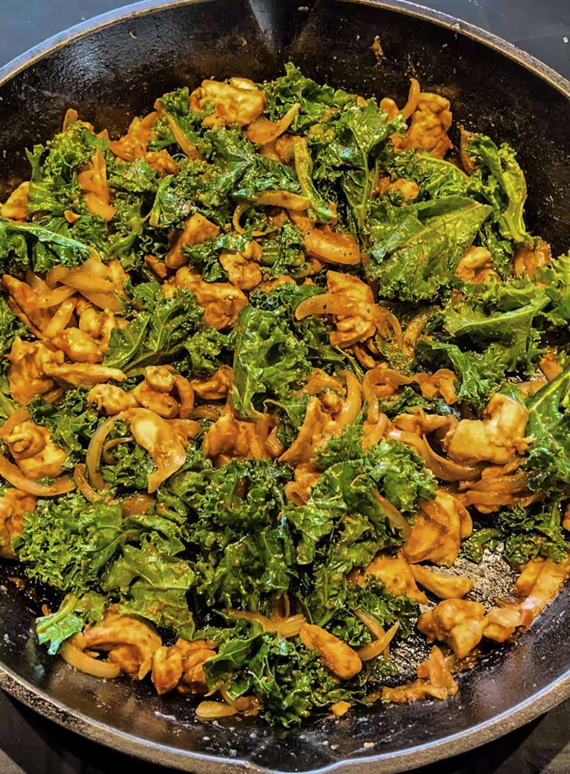 adobo inspired chicken and kale taco filling cooking in a large cast iron pan