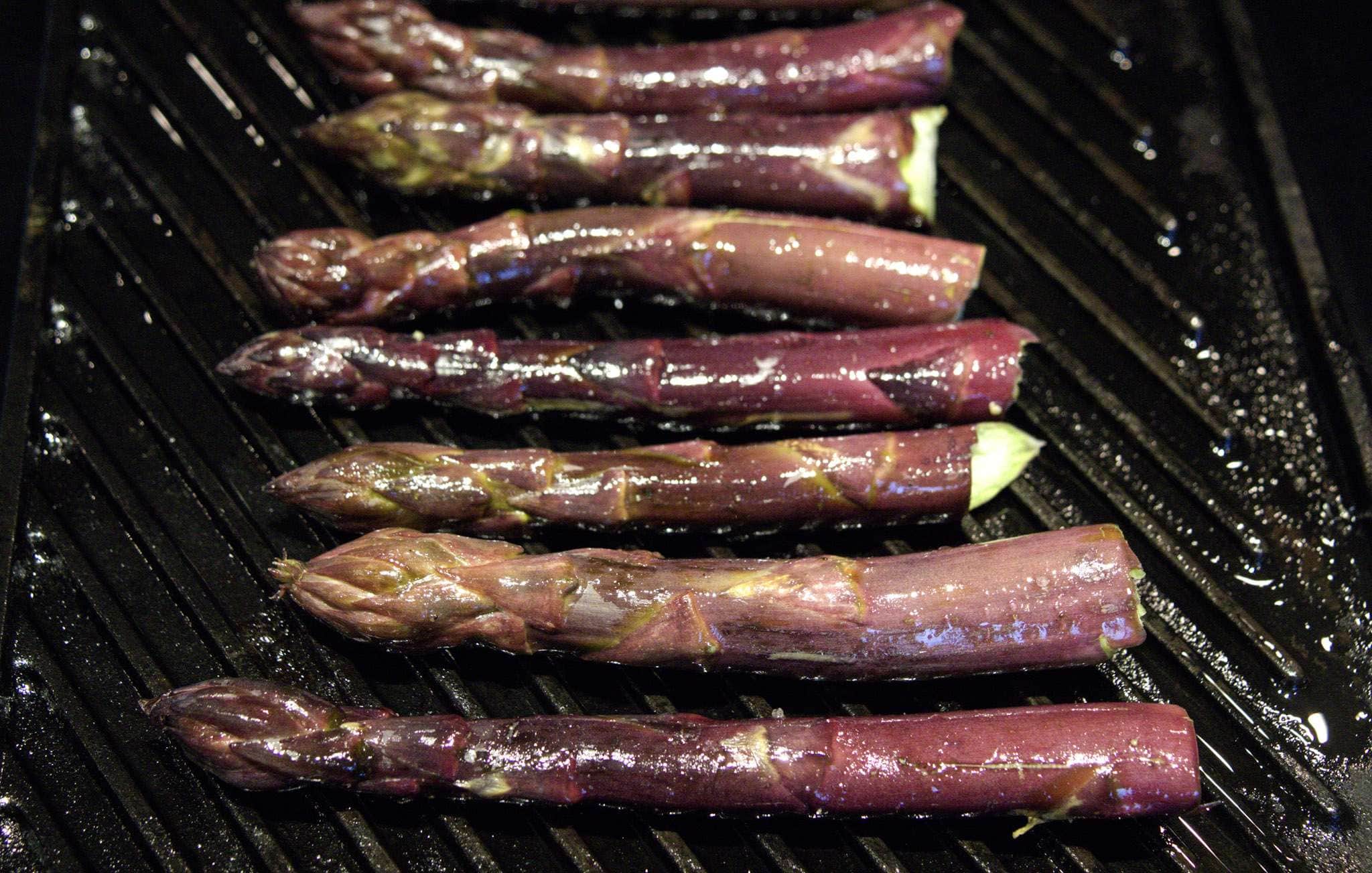 Purple asparagus spears cooking on a grill pan