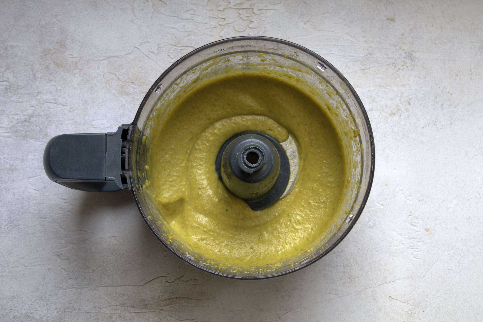 A food processor bowl containing the just processed dairy-free pistachio lime cream
