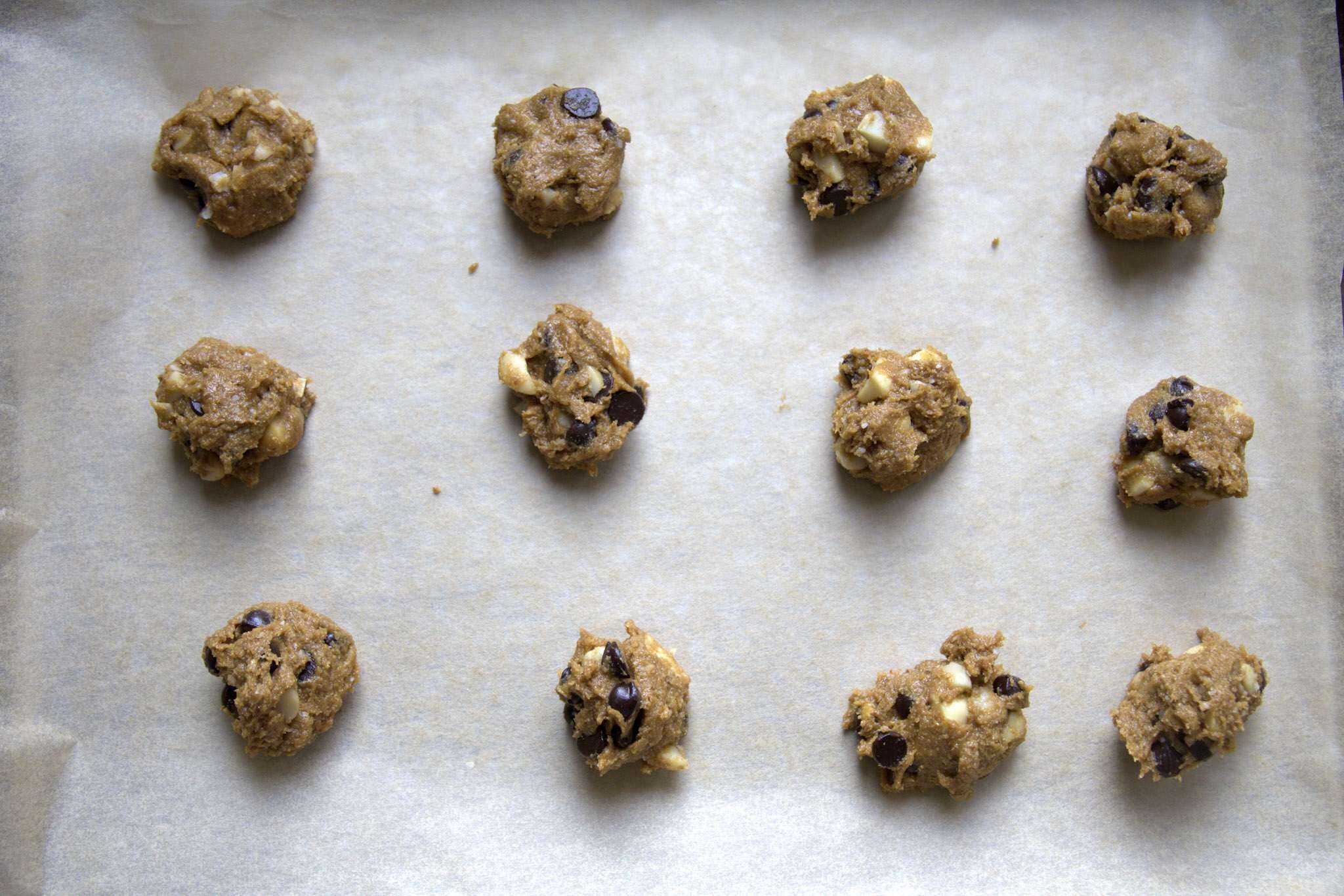 gluten free chocolate chip macadamia cookie dough balls on a parchment lined baking sheet