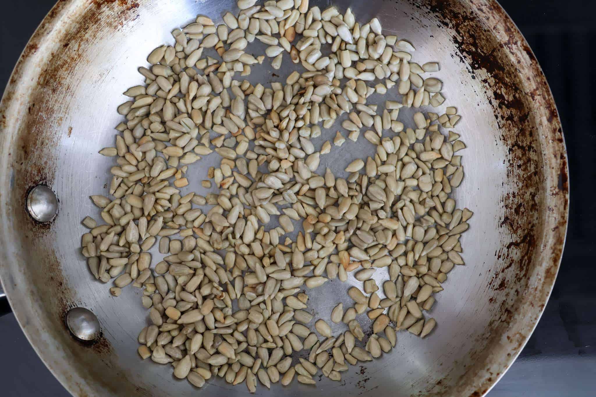Sunflower seeds are toasting in a stainless steel pan