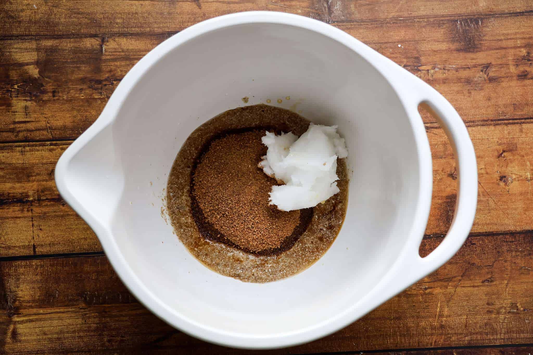 the wet ingredients for delicious gluten-free chocolate chip macadamia cookies are displayed in a white bowl, which is placed on a wooden surface