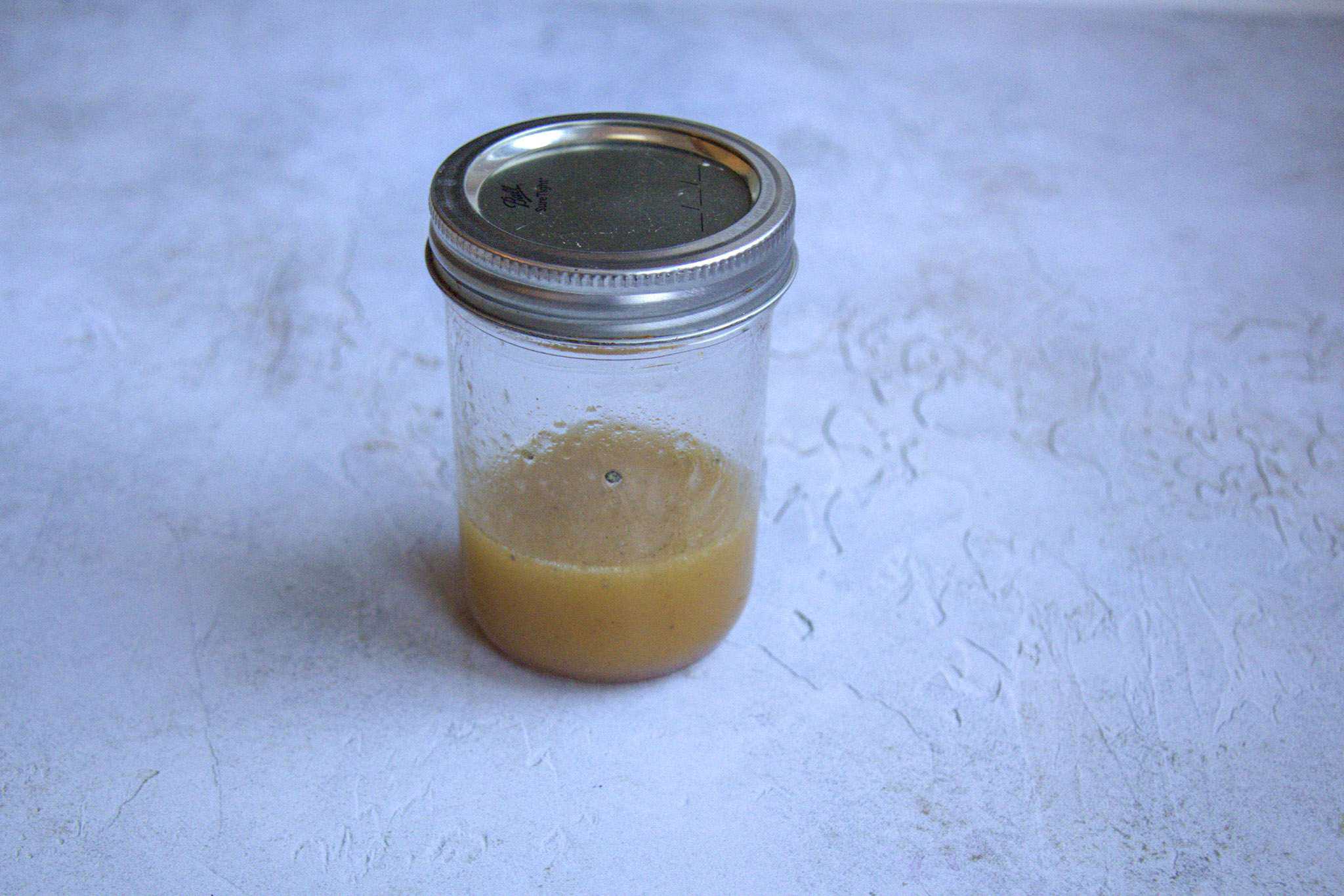 A jar with dressing for crunchy beet and carrot slaw with apples