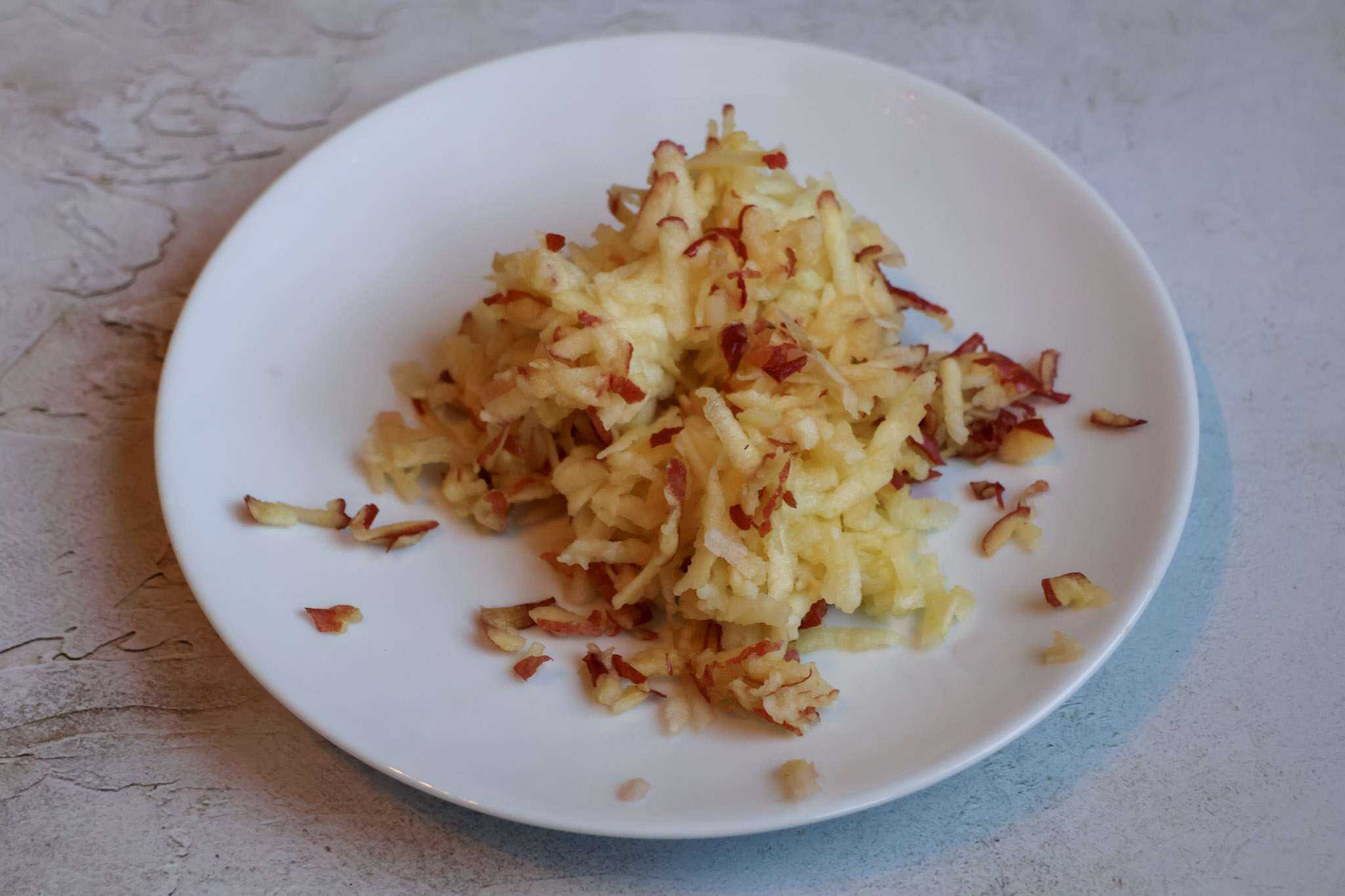 A white plate with grated apple
