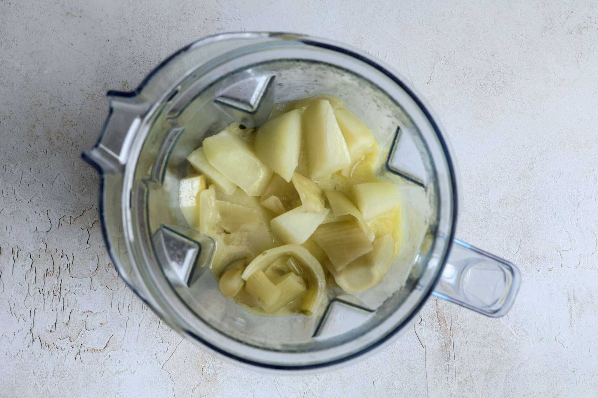 A blender container with the ingredients for spiced kohlrabi, fennel and apple soup ready to be blended