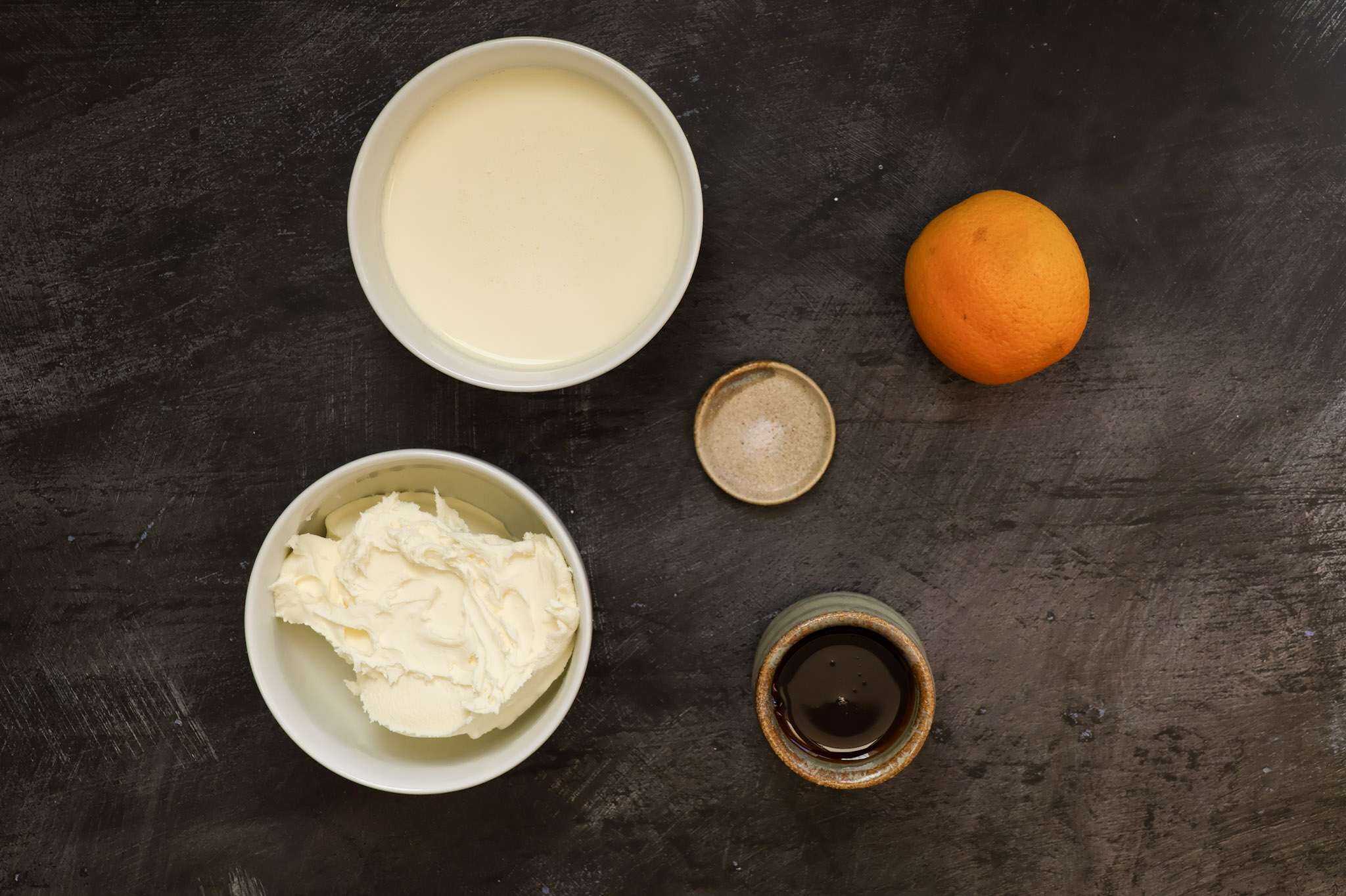 Ingredients for Orange Mascarpone Frosting displayed on a dark concrete style background
