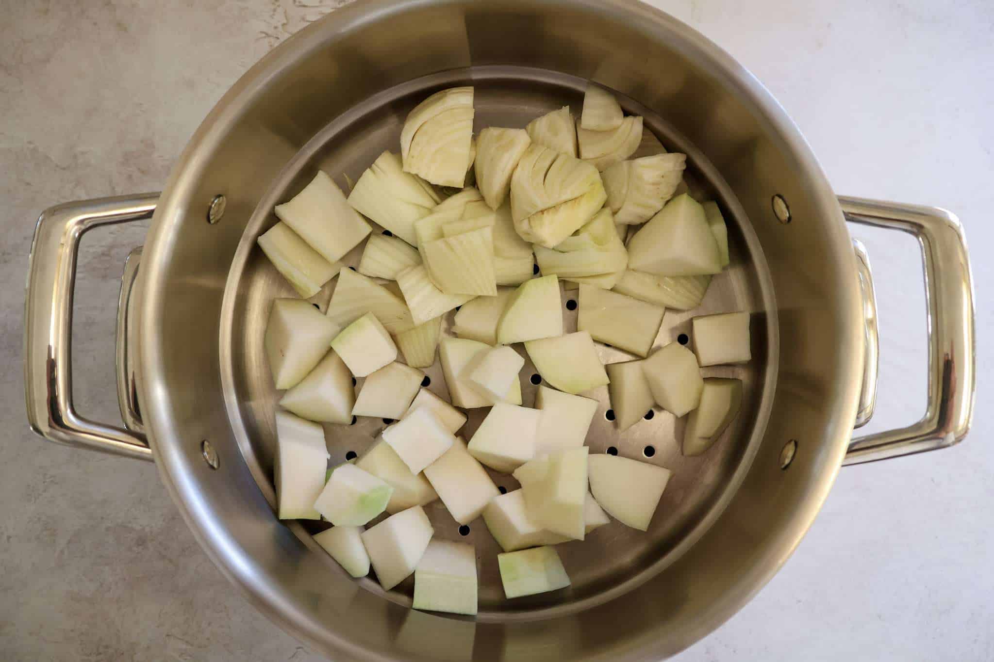 A steamer basket with chopped fennel and kohlrabi