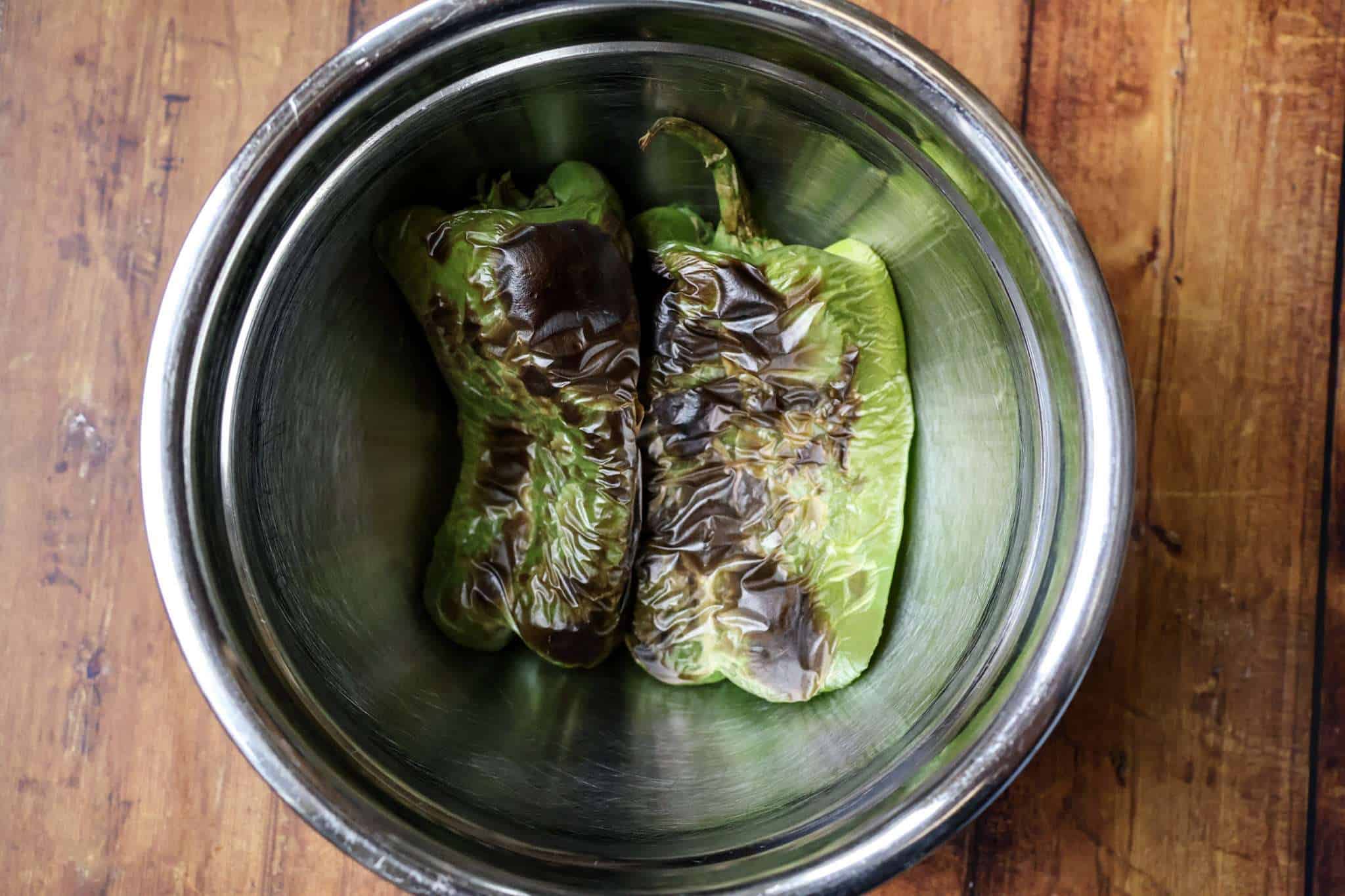 A metal bowl holding two roasted bell peppers