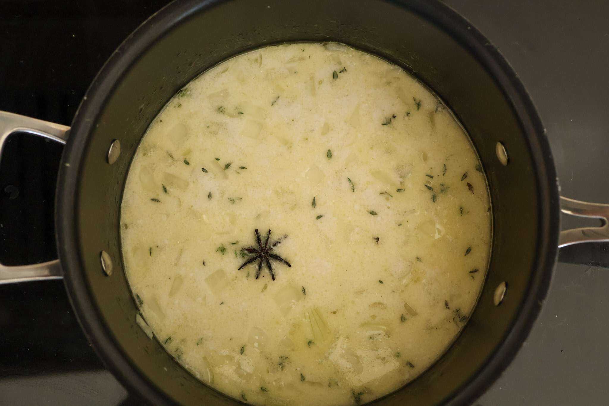 Sauteed onions, garlic, thyme, and star anise simmering in a pot