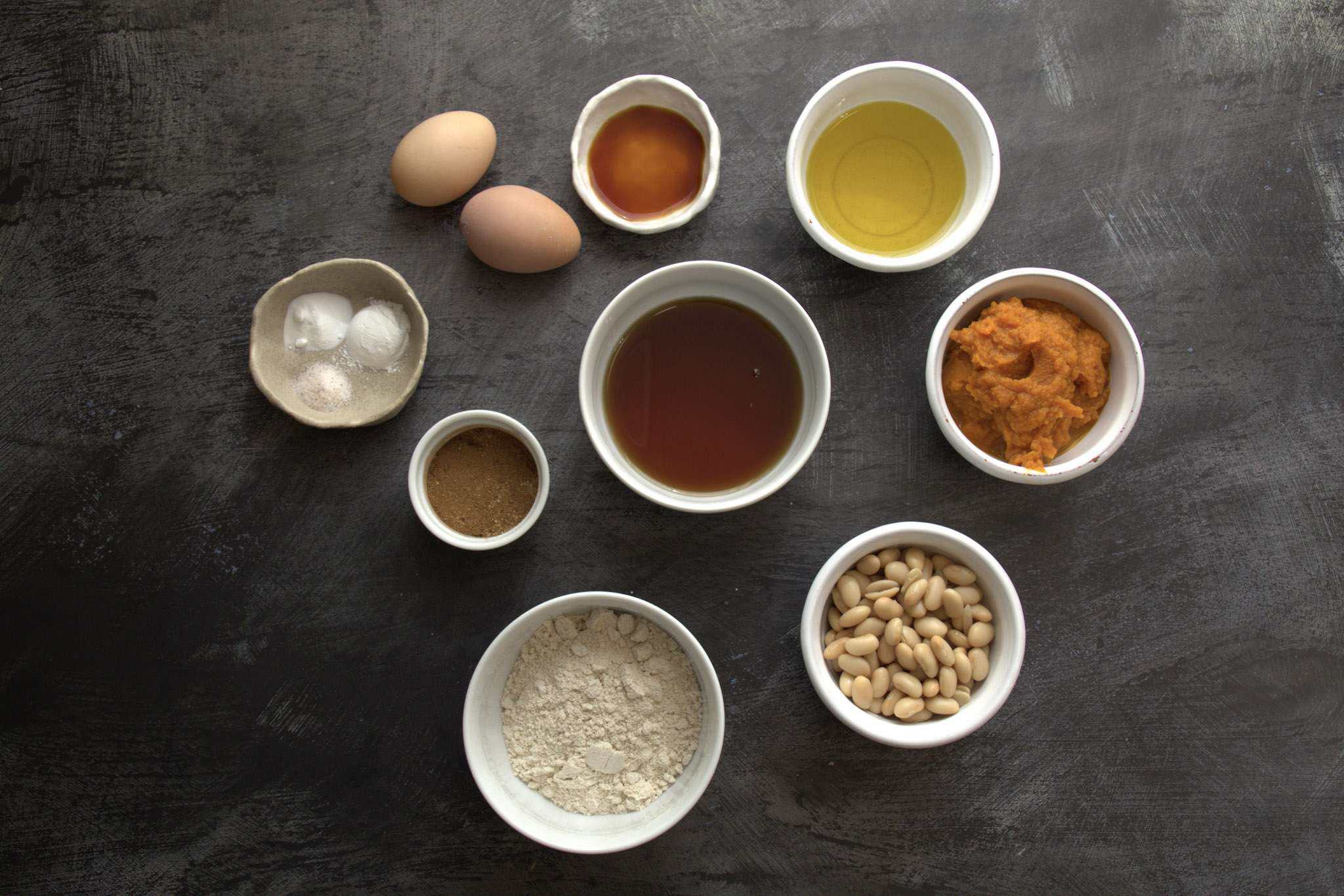 All ingredients for Soft and Fluffy Pumpkin Bars (with White Beans and a Healthy Twist) displayed on a dark concrete style background