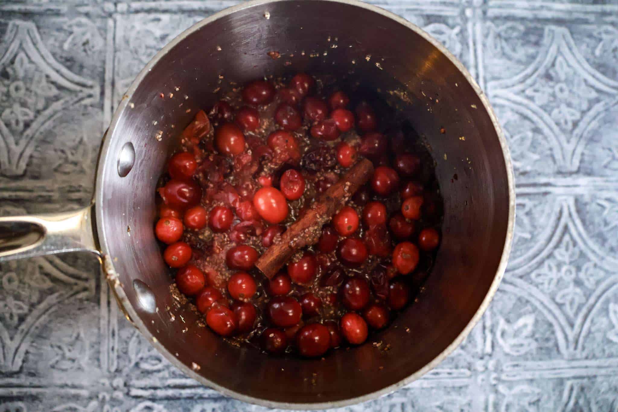 a small pot with all ingredients for cranberry chia jam with orange and ginger partially cooked