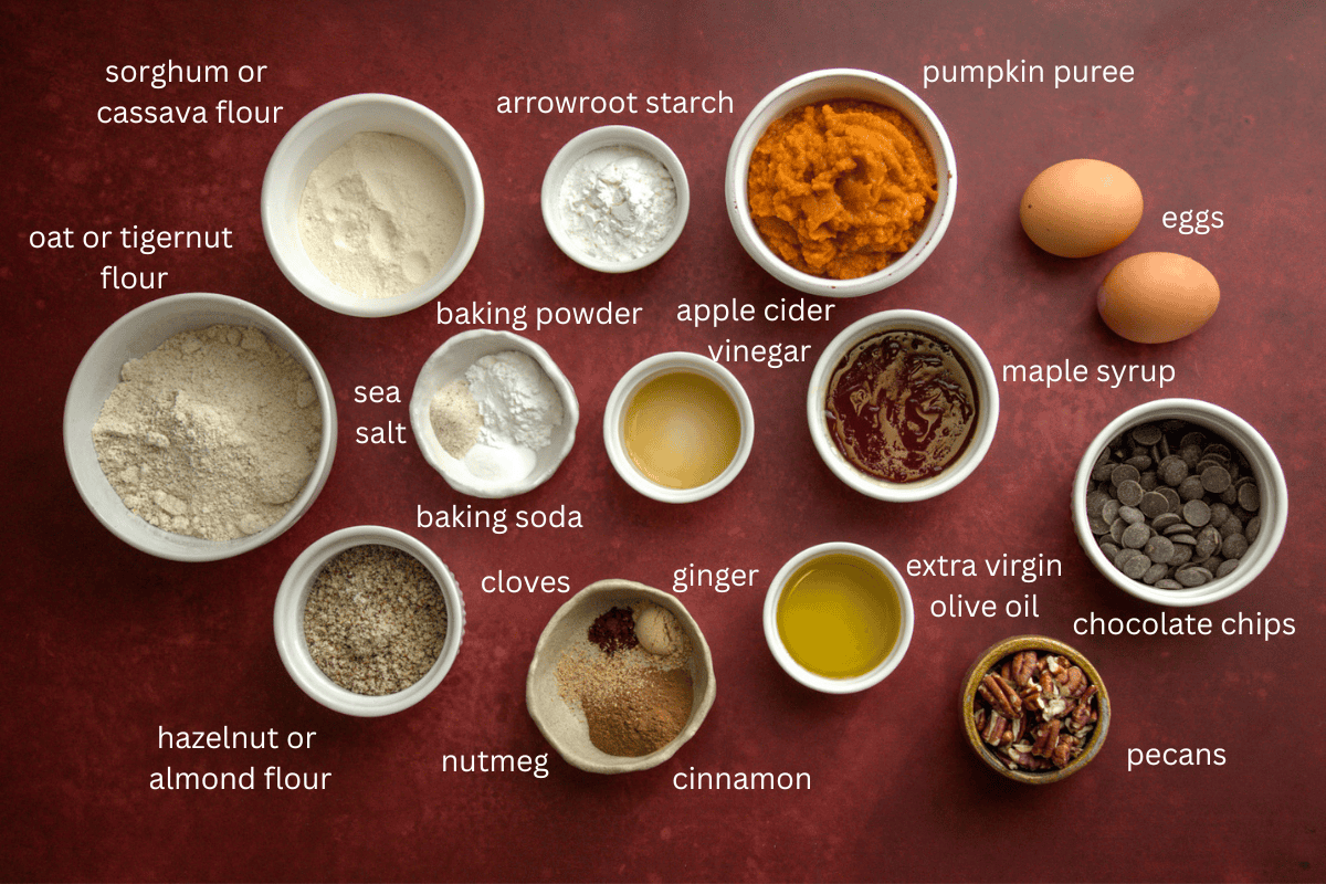 All ingredients for tender gluten-free pumpkin muffins (dairy-free) are displayed on a red surface and labeled