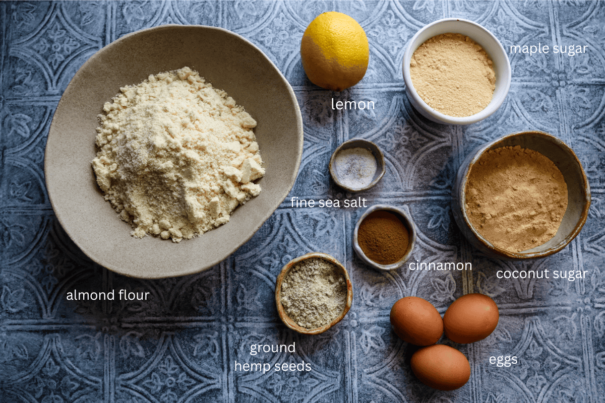 All ingredients for healthier zimtsterne cookies are displayed on a textured gray surface and labeled