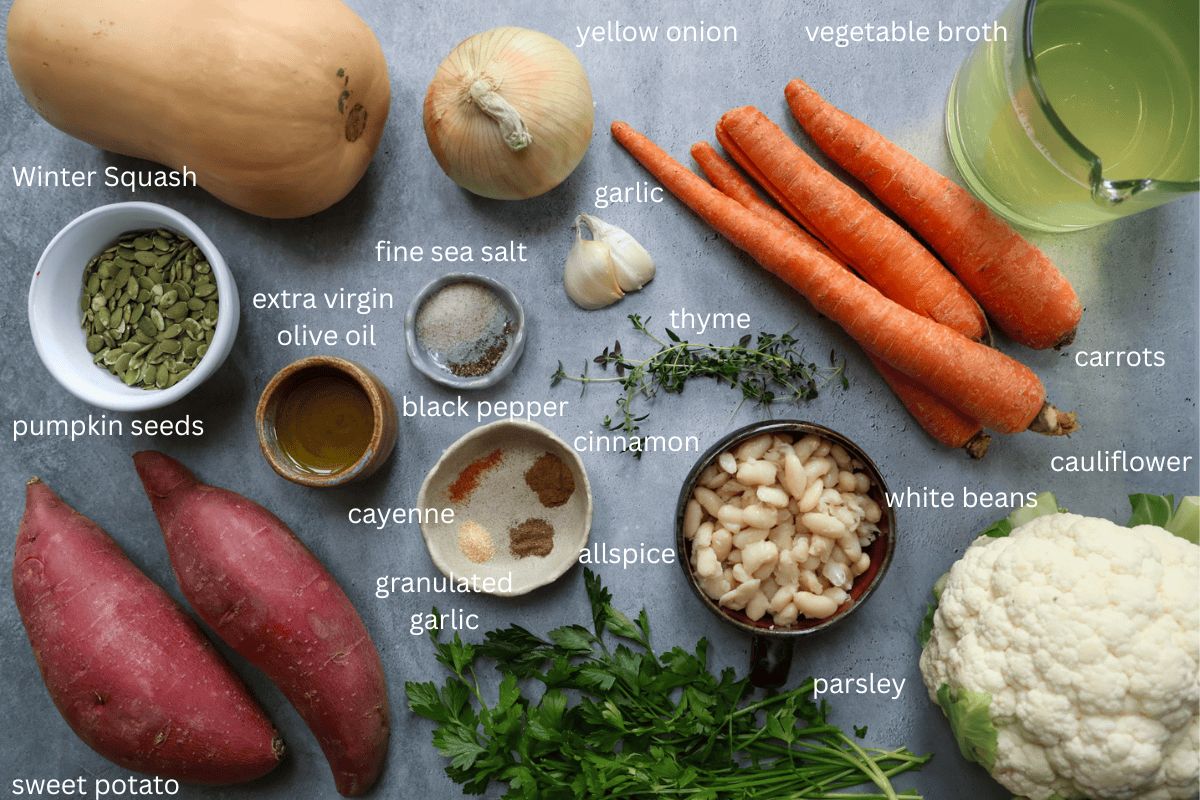 all ingredients for creamy winter vegetable soup are displayed on a grey concrete style surface and labeled